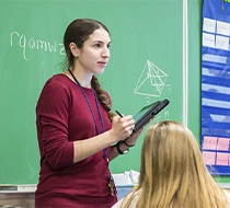 female student standing next to the blackboard
