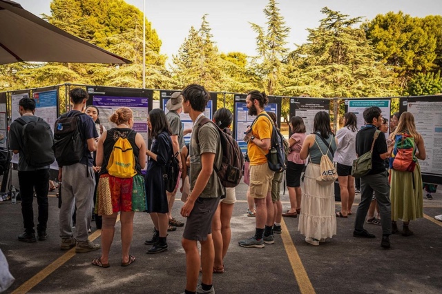 An image of an educational conference. Attendees are socializing and looking at posters.