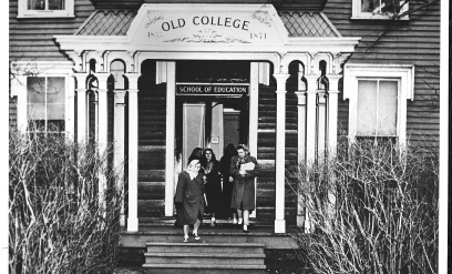 A group of students stand on the steps of The Old School.