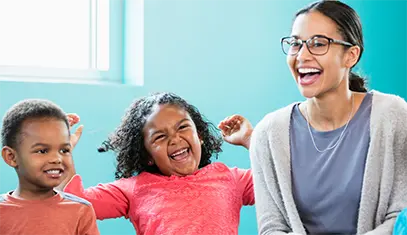 elementary teacher laughing with two children