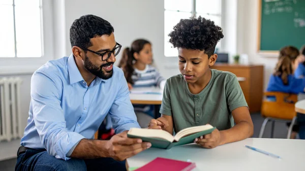 A teacher and a secondary student read and discuss a book.