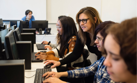 An image of a teacher working with students in a computer lab.