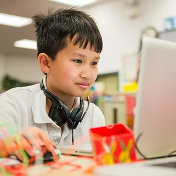 A child wearing headphones and looking at a computer