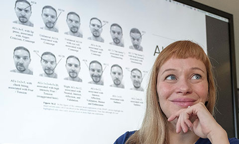 Claudia Haase in front of a screen showing facial expressions