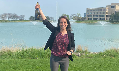Dr. Naomi Blaushild holding a bottle of champagne aloft